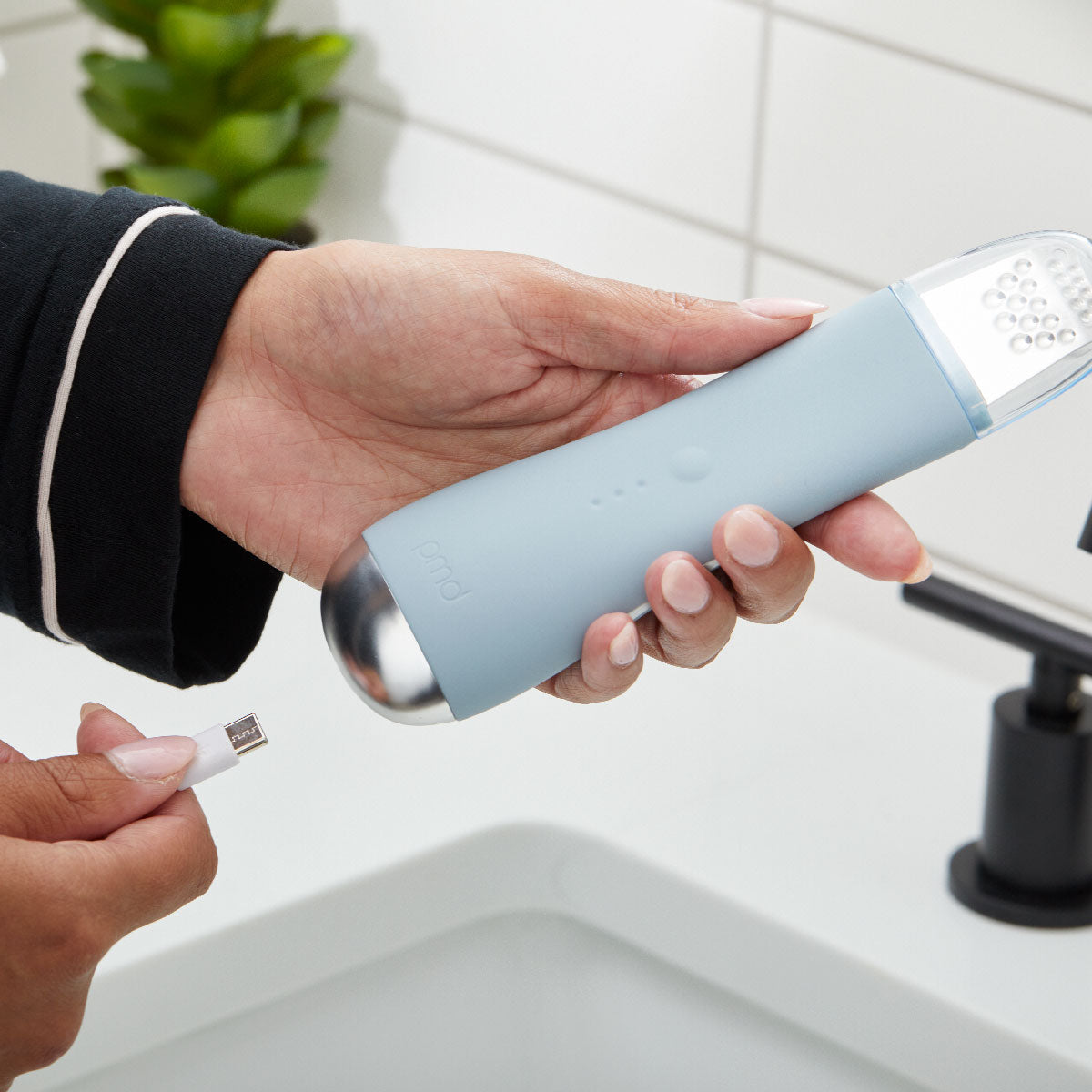 woman inserting charging cord into bottom of PMD Wave Pro